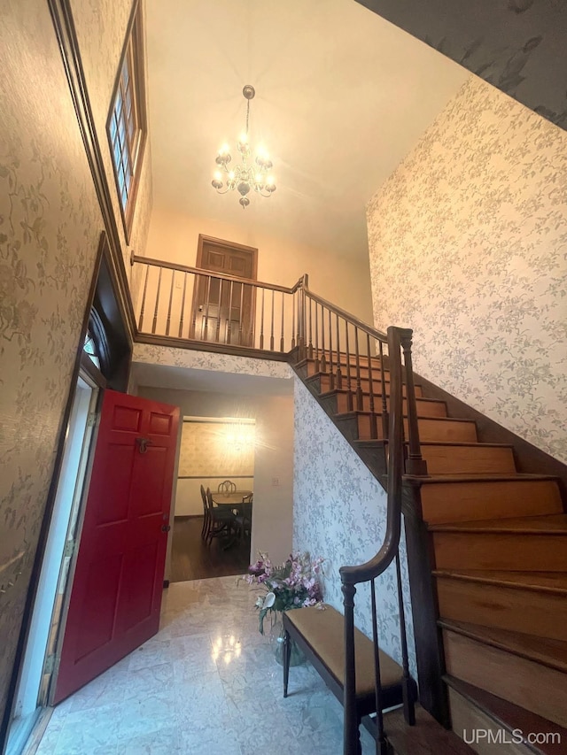 stairway featuring a chandelier, wood-type flooring, and a towering ceiling