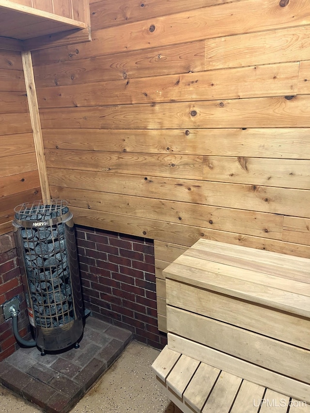 view of sauna featuring wooden walls and brick wall