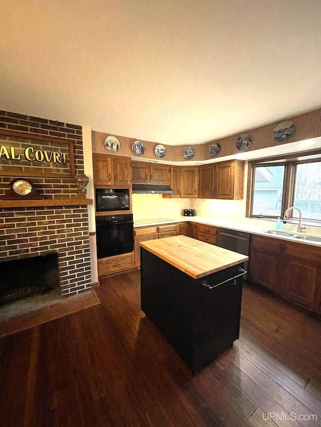 kitchen with sink, black appliances, a center island, dark hardwood / wood-style floors, and butcher block counters