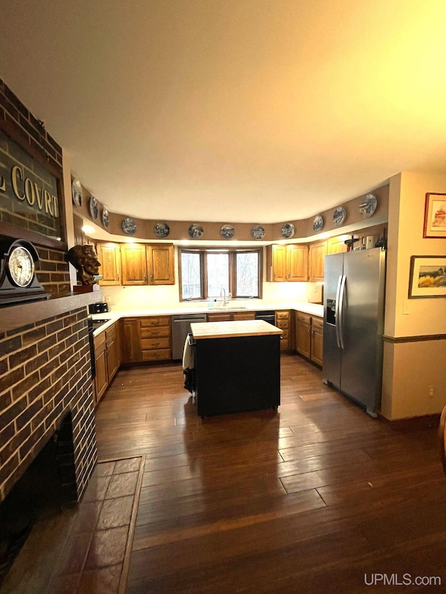 kitchen with sink, dark hardwood / wood-style floors, a fireplace, a kitchen island, and stainless steel appliances