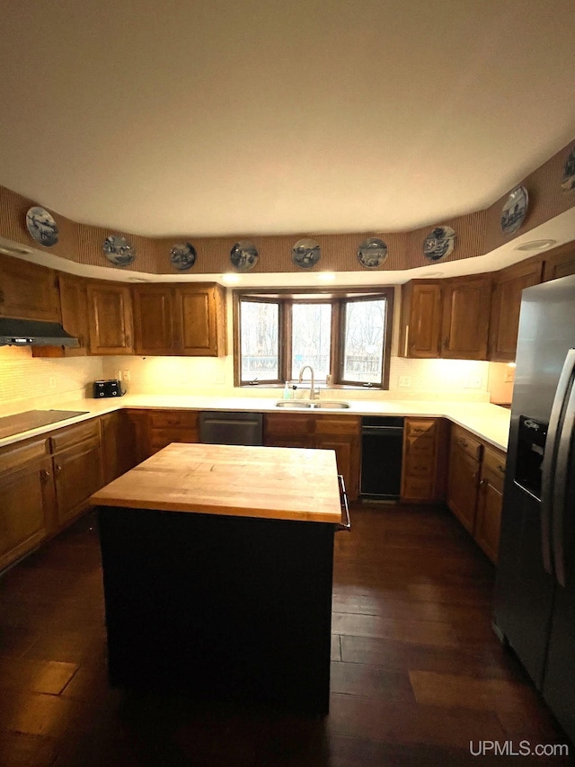 kitchen with wooden counters, appliances with stainless steel finishes, a center island, and sink