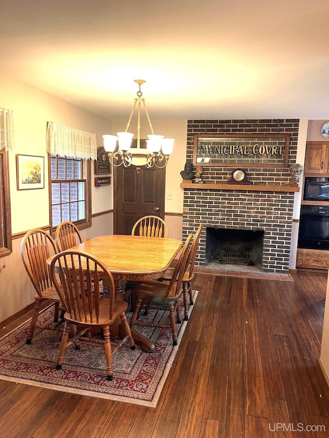 dining area with hardwood / wood-style flooring, a fireplace, and an inviting chandelier