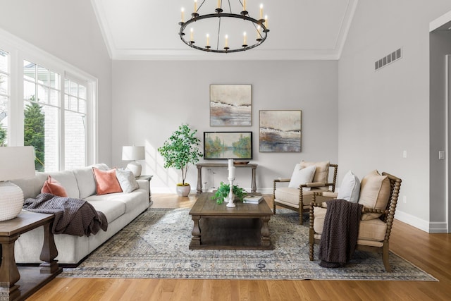 living area featuring crown molding, a chandelier, wood finished floors, vaulted ceiling, and baseboards