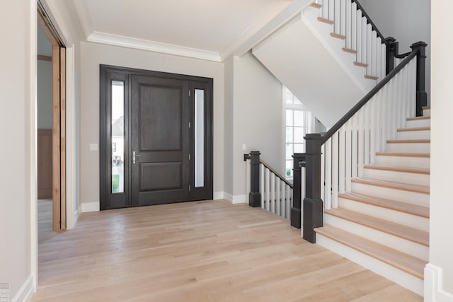 foyer with light wood-type flooring and crown molding