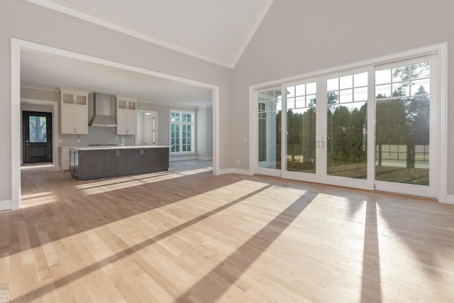 unfurnished living room featuring light wood-type flooring, high vaulted ceiling, and ornamental molding