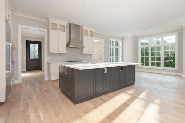 kitchen featuring a wealth of natural light, a kitchen island with sink, and wall chimney range hood