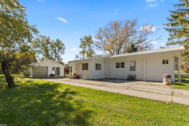 rear view of house with a garage, a lawn, and an outdoor structure