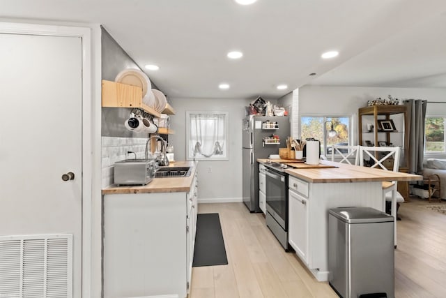 kitchen featuring butcher block countertops, stainless steel appliances, white cabinetry, backsplash, and light hardwood / wood-style flooring