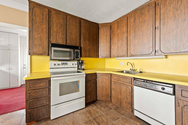 kitchen with white appliances, a textured ceiling, and sink