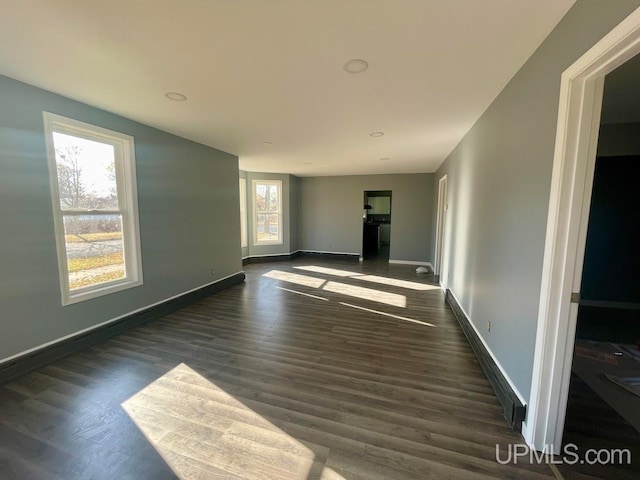 spare room featuring plenty of natural light and dark wood-type flooring