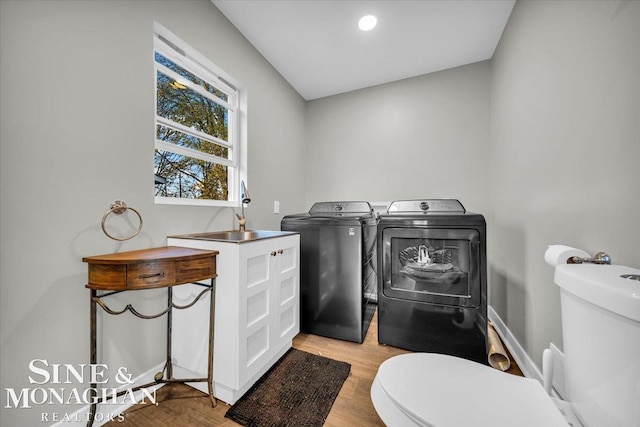 washroom featuring sink, washing machine and clothes dryer, and light hardwood / wood-style flooring