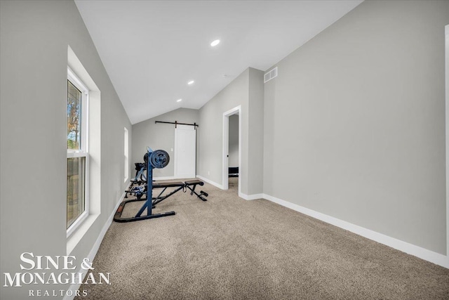 workout room with a barn door, carpet flooring, and vaulted ceiling