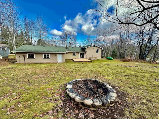 back of house with a wooden deck, a yard, and a fire pit