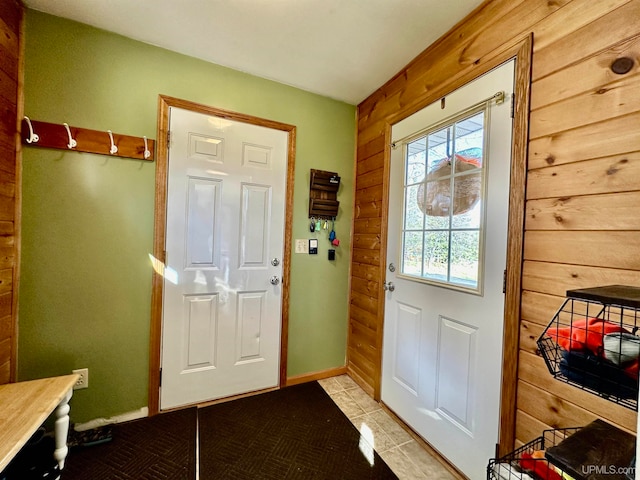 doorway to outside with wood walls and light tile patterned floors