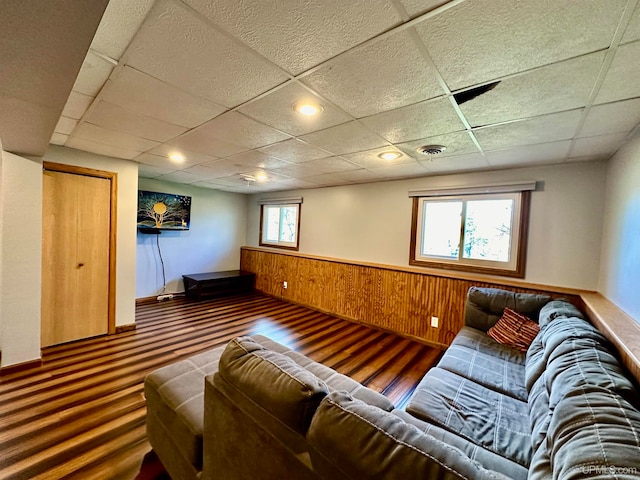 living room featuring plenty of natural light, a drop ceiling, and wood-type flooring