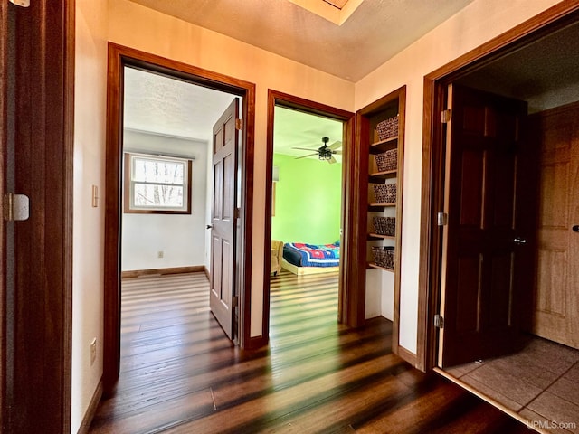 corridor with a textured ceiling and dark wood-type flooring