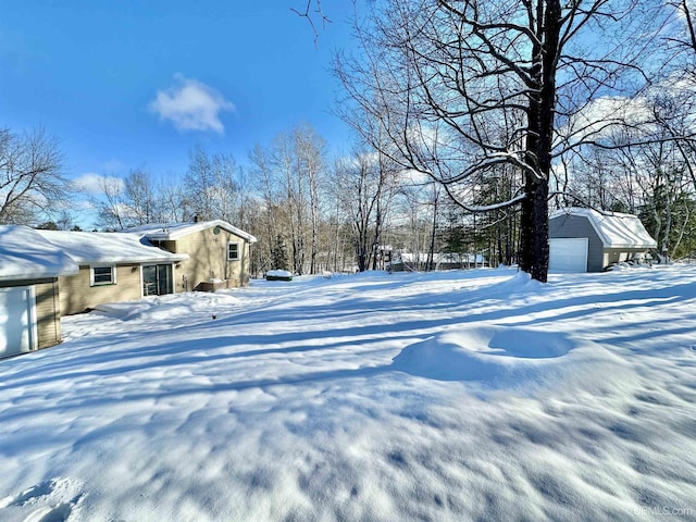 yard layered in snow with a garage and an outdoor structure