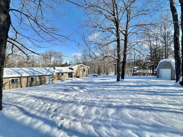 yard covered in snow with an outbuilding and a garage