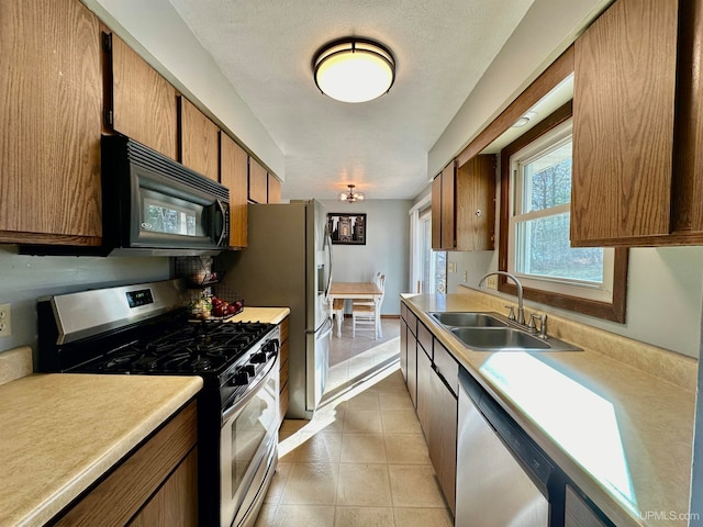 kitchen with a textured ceiling, sink, light tile patterned floors, and stainless steel appliances