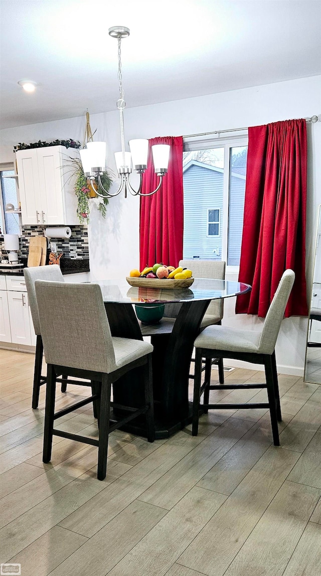 dining space featuring hardwood / wood-style flooring, a wealth of natural light, and an inviting chandelier