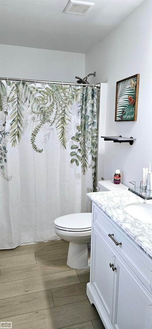 bathroom featuring wood-type flooring, curtained shower, vanity, and toilet