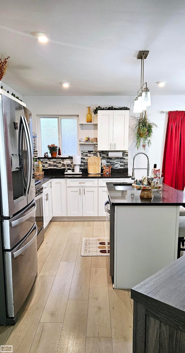 kitchen with sink, white cabinetry, light hardwood / wood-style floors, stainless steel fridge with ice dispenser, and decorative light fixtures