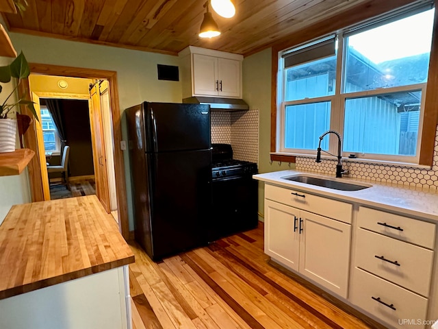 kitchen featuring white cabinets, black appliances, sink, tasteful backsplash, and light hardwood / wood-style flooring