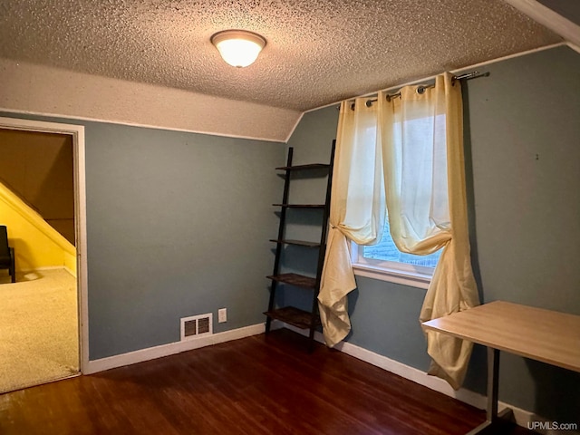 unfurnished bedroom featuring dark hardwood / wood-style flooring, a textured ceiling, and lofted ceiling