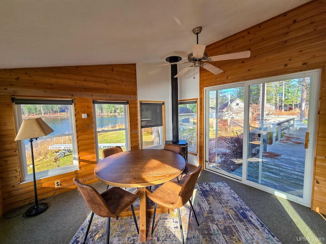 carpeted dining area featuring vaulted ceiling, a wealth of natural light, and wooden walls