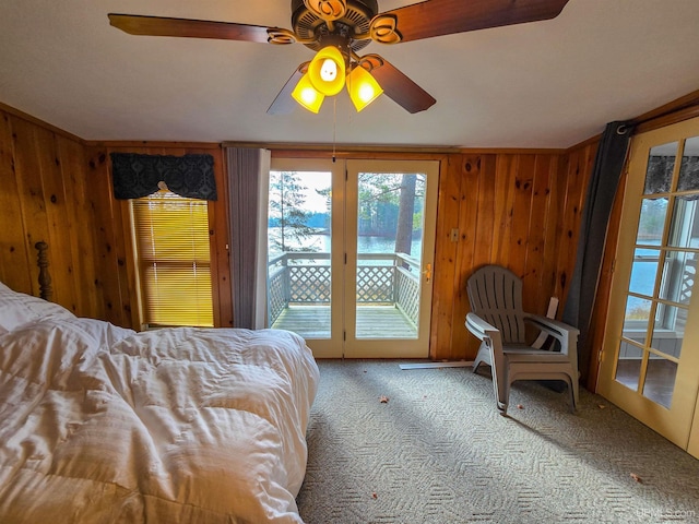 unfurnished bedroom with access to exterior, carpet, wooden walls, and a ceiling fan