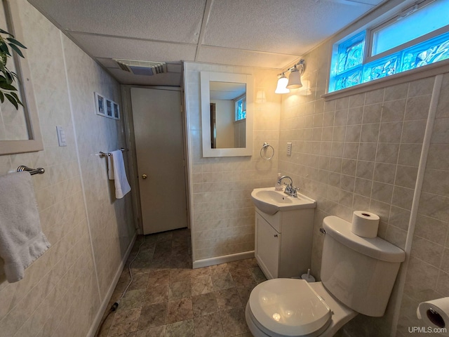 bathroom with toilet, visible vents, tile walls, and vanity