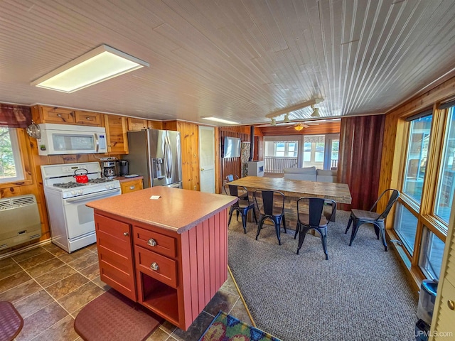 kitchen featuring white appliances, a healthy amount of sunlight, and wooden walls