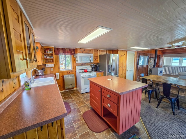 kitchen featuring white appliances, wood walls, a sink, and a healthy amount of sunlight