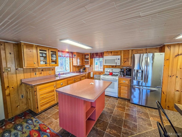 kitchen featuring open shelves, white appliances, a center island, and wooden walls