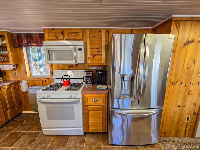 kitchen with brown cabinetry, white appliances, wooden ceiling, and wooden walls