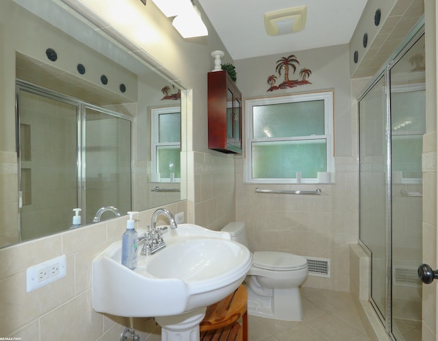 bathroom with toilet, tile walls, tile patterned flooring, sink, and a shower with shower door