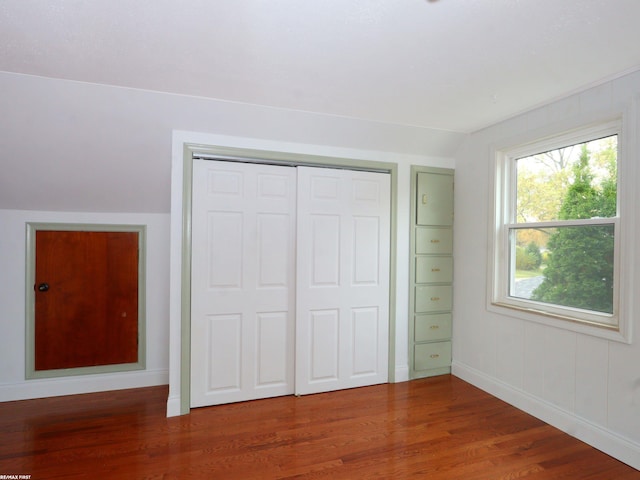 unfurnished bedroom with wood-type flooring, a closet, and vaulted ceiling