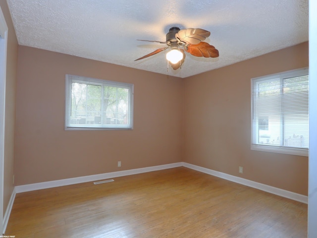 unfurnished room with ceiling fan, a healthy amount of sunlight, light wood-type flooring, and a textured ceiling