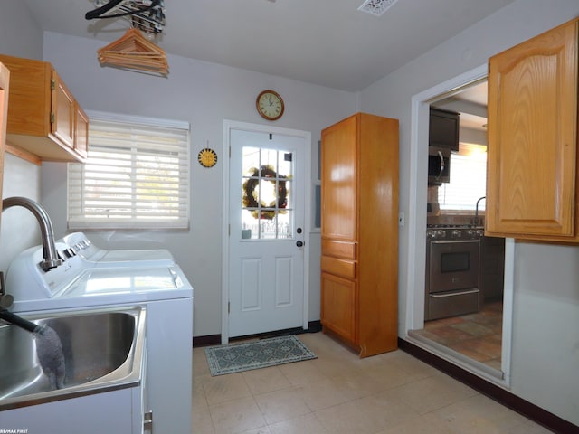 clothes washing area with cabinets, sink, and washer and clothes dryer