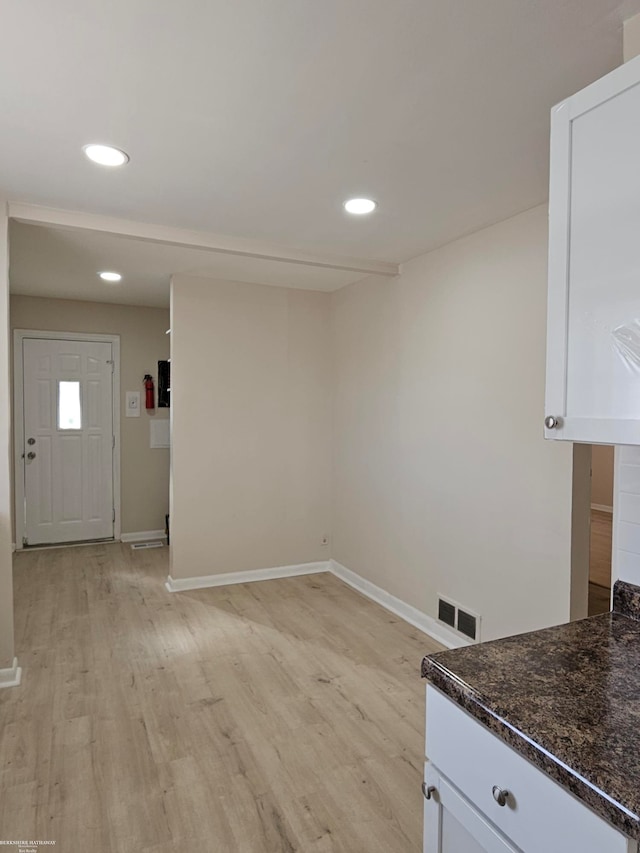 interior space with white cabinetry, light hardwood / wood-style floors, and dark stone countertops