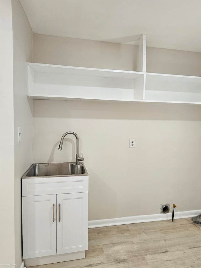 laundry area with light wood-type flooring, cabinets, and sink