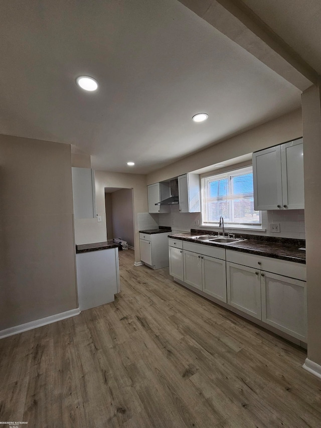 kitchen featuring white cabinets, wall chimney exhaust hood, sink, and light wood-type flooring