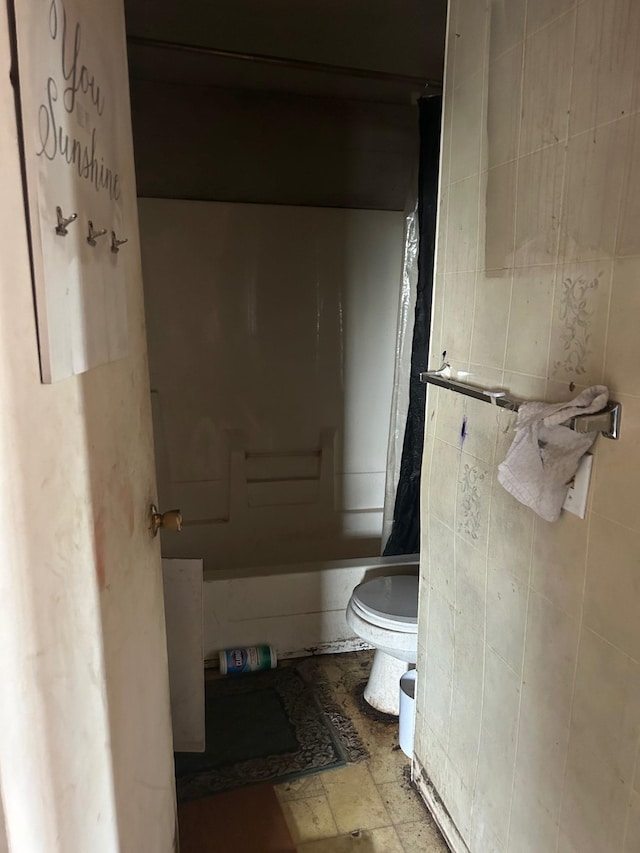 bathroom featuring toilet and tile walls