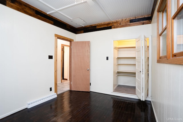 spare room featuring wooden walls, baseboard heating, and dark hardwood / wood-style floors