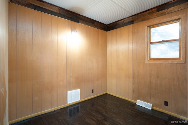 spare room featuring wood walls and dark wood-type flooring