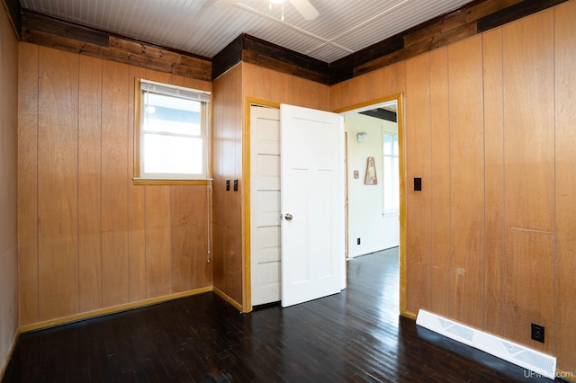 empty room featuring ceiling fan, wooden walls, and dark hardwood / wood-style flooring