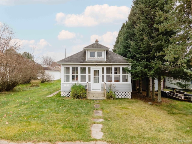 bungalow-style home with a front lawn and a sunroom