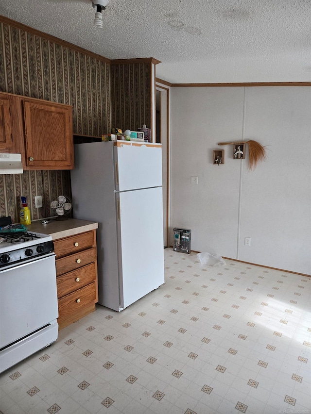 kitchen with a textured ceiling, white appliances, and ornamental molding