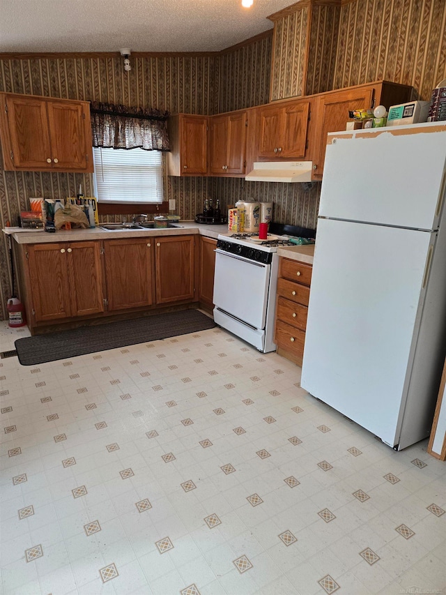 kitchen featuring a textured ceiling, white appliances, and sink