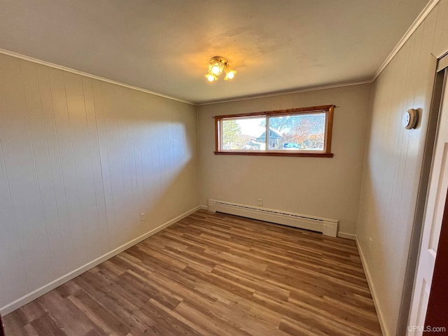 empty room with wooden walls, wood-type flooring, ornamental molding, and a baseboard radiator